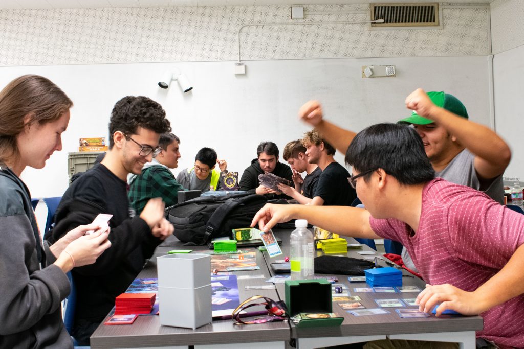 Various Cal Poly Pomona students, all a part of Cal Poly Pomona's Gamer's Union, playing board games and cheering as they win.